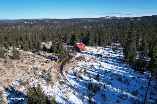 snowy aerial view with a mountain view and a forest view