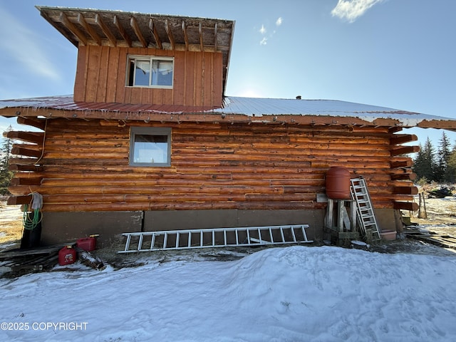 snow covered property with log exterior and metal roof