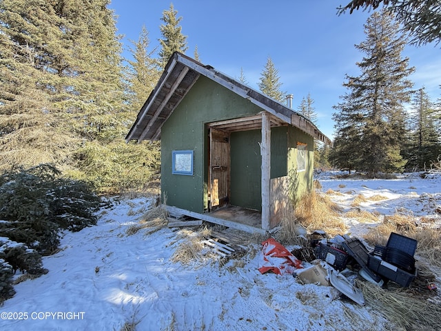 snow covered structure featuring an outdoor structure and a shed