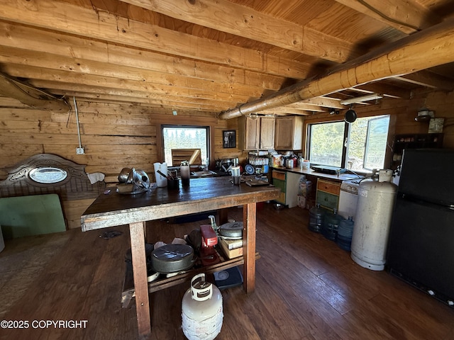 kitchen with beamed ceiling, wood walls, freestanding refrigerator, and dark wood-type flooring