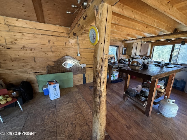 interior space with wooden walls, wood finished floors, and beamed ceiling