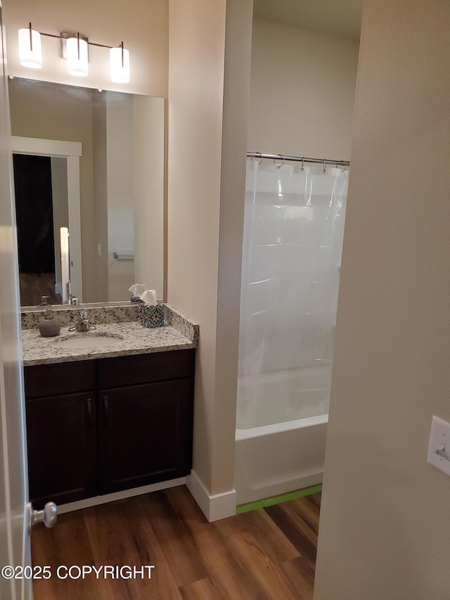 bathroom featuring baseboards, wood finished floors, vanity, and shower / tub combo with curtain