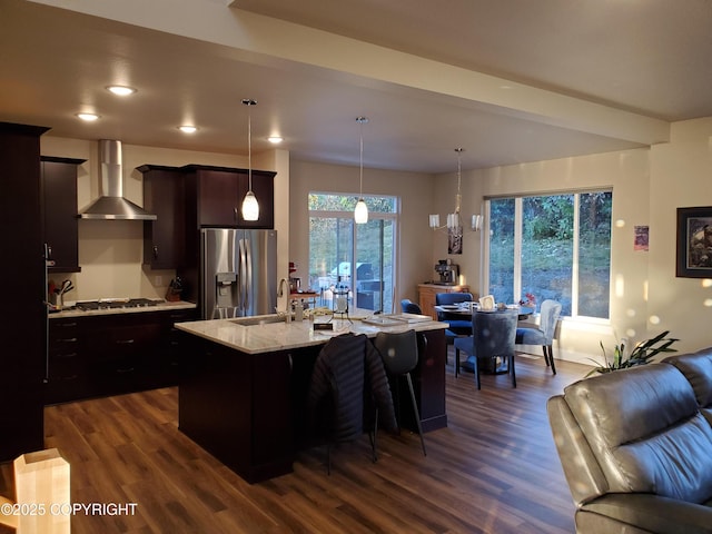 kitchen with appliances with stainless steel finishes, open floor plan, a sink, and wall chimney range hood