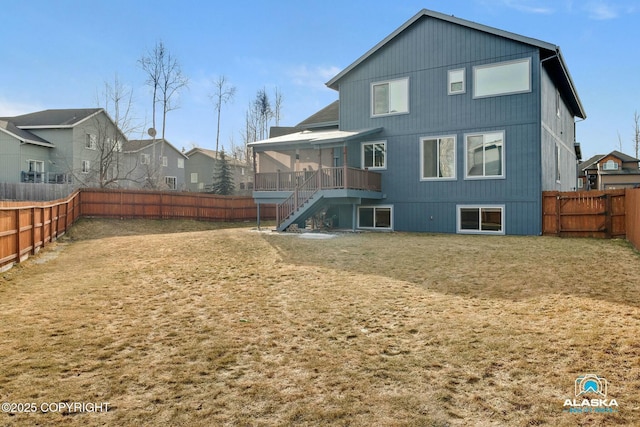 back of property featuring stairs, a fenced backyard, and a lawn