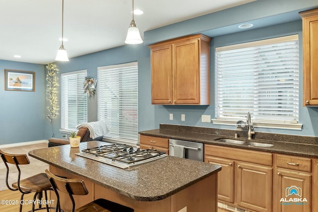 kitchen with a kitchen island, decorative light fixtures, a breakfast bar area, appliances with stainless steel finishes, and a sink