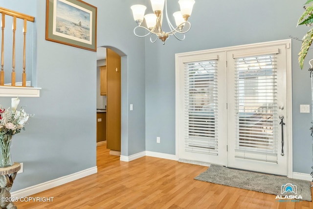 dining area featuring baseboards, arched walkways, and wood finished floors