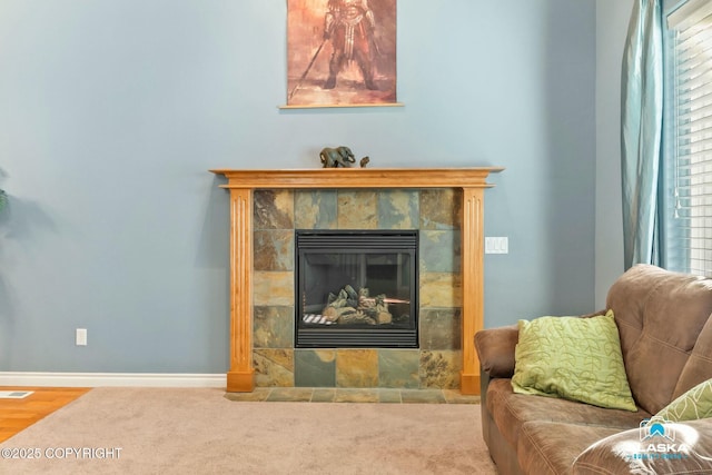 living area featuring carpet flooring, baseboards, and a tile fireplace