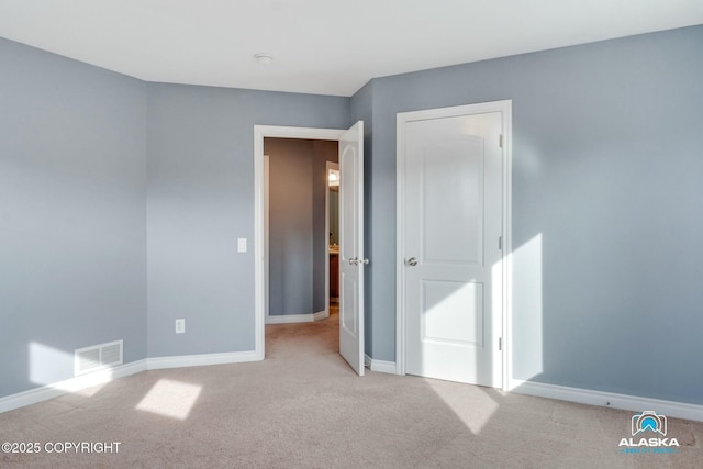 unfurnished bedroom with carpet flooring, baseboards, and visible vents