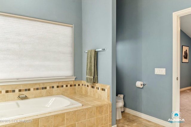 bathroom featuring baseboards, toilet, and a bath