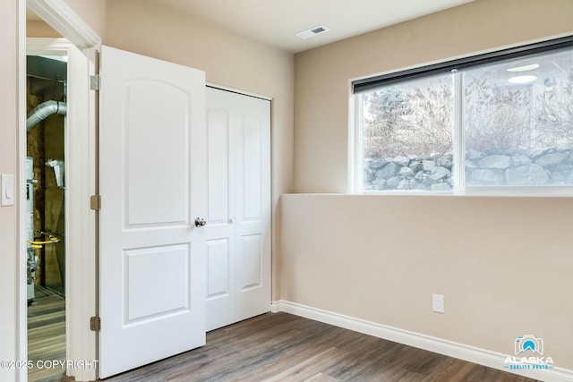 unfurnished bedroom featuring visible vents, wood finished floors, a closet, and baseboards