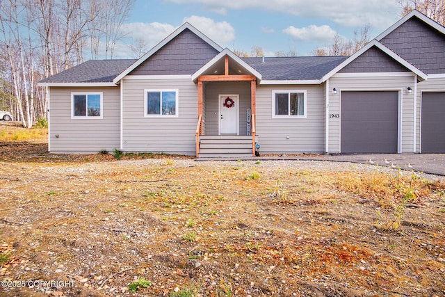 ranch-style house featuring aphalt driveway, a shingled roof, and an attached garage