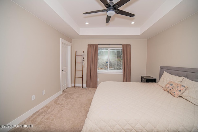 bedroom with a tray ceiling, recessed lighting, a ceiling fan, light carpet, and baseboards