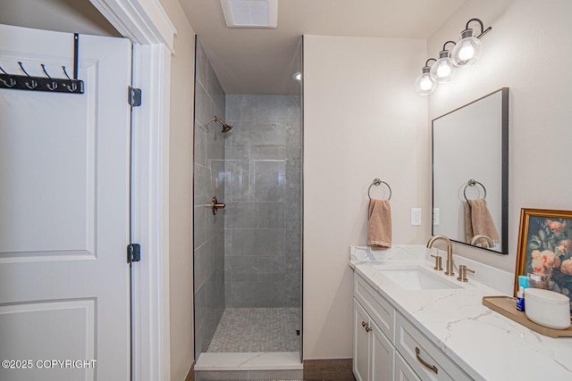 bathroom featuring a tile shower, vanity, and visible vents