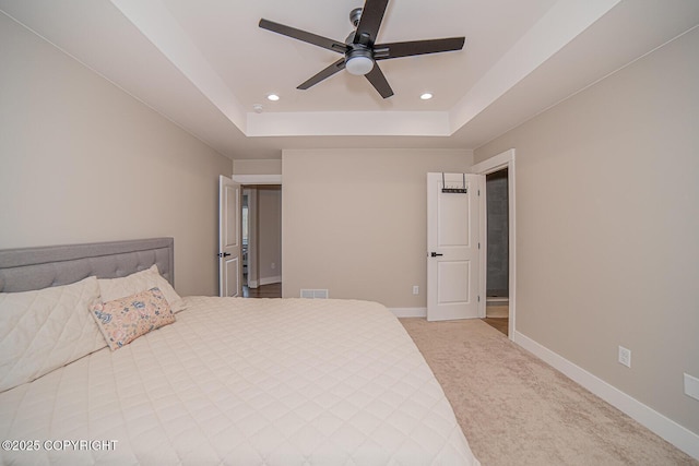 bedroom with a tray ceiling, light colored carpet, baseboards, and recessed lighting