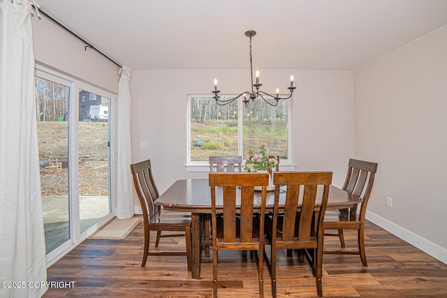 dining space featuring dark wood-style flooring, a notable chandelier, and baseboards