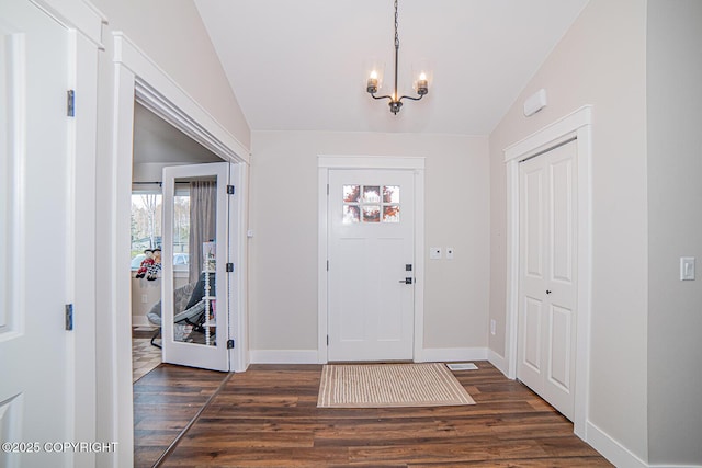 entryway featuring a chandelier, lofted ceiling, dark wood-style flooring, and baseboards