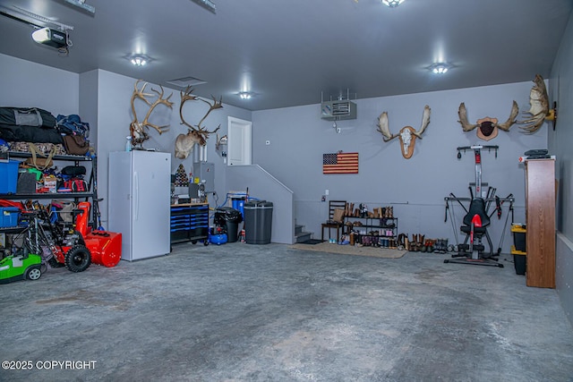 garage with a garage door opener, freestanding refrigerator, and a workshop area