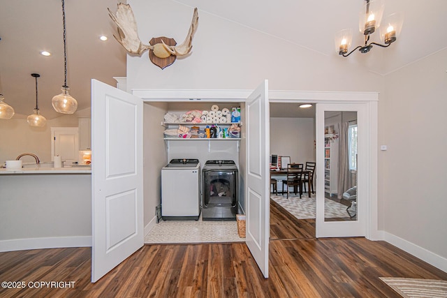 interior space with laundry area, dark wood-style flooring, washing machine and clothes dryer, and an inviting chandelier