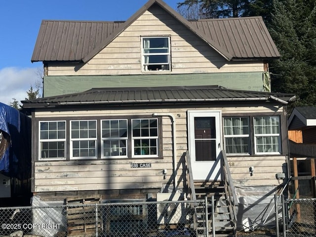 view of front of property featuring entry steps, metal roof, and fence