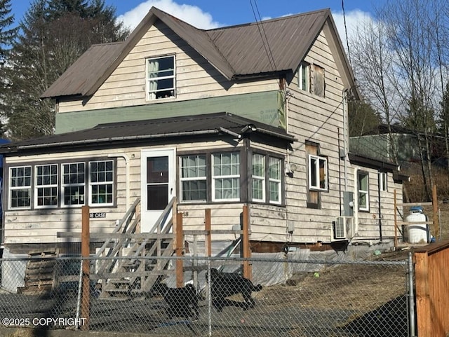 view of front of home with entry steps, metal roof, and a fenced front yard