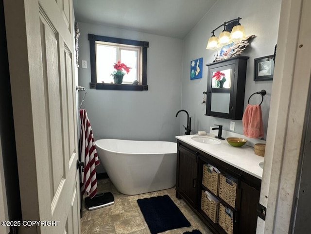 full bath featuring a soaking tub, a sink, stone finish flooring, and double vanity