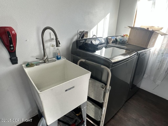 washroom with a textured wall, laundry area, dark wood-type flooring, a sink, and washer and dryer