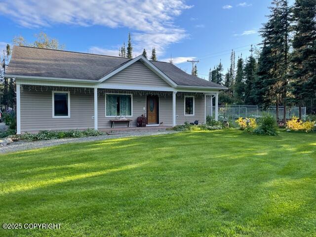 view of front of house with covered porch, a front yard, and fence