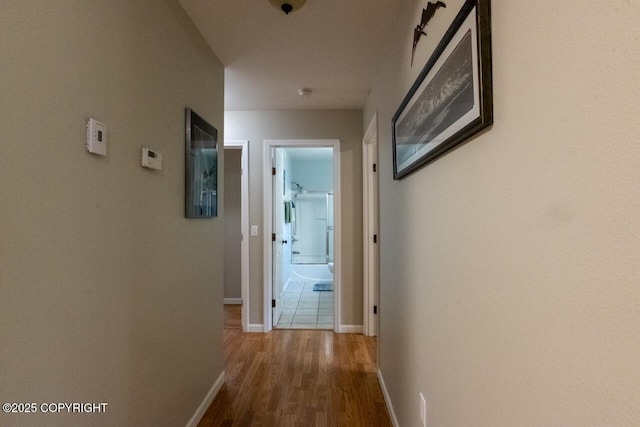 corridor featuring wood finished floors and baseboards