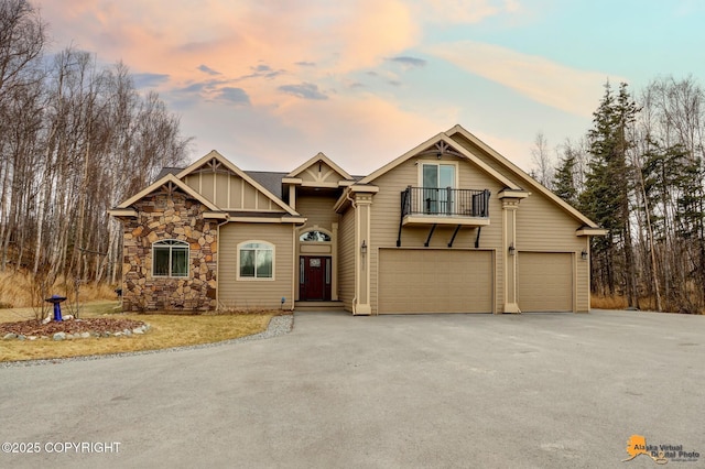 view of front of property with driveway, a balcony, stone siding, an attached garage, and board and batten siding