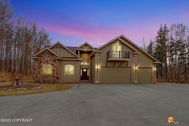 view of front of house featuring board and batten siding, a balcony, a garage, stone siding, and driveway