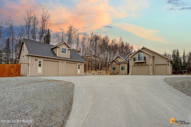 view of front facade with a garage, driveway, and fence