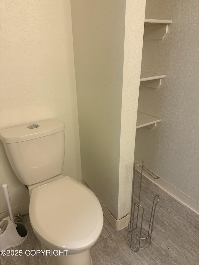 bathroom with toilet and a textured wall