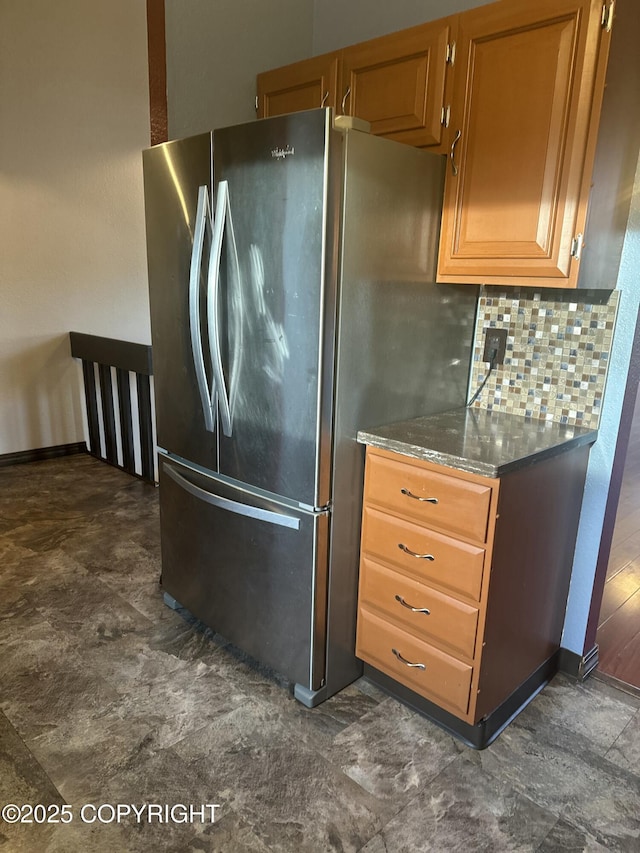 kitchen with freestanding refrigerator, backsplash, and dark stone countertops