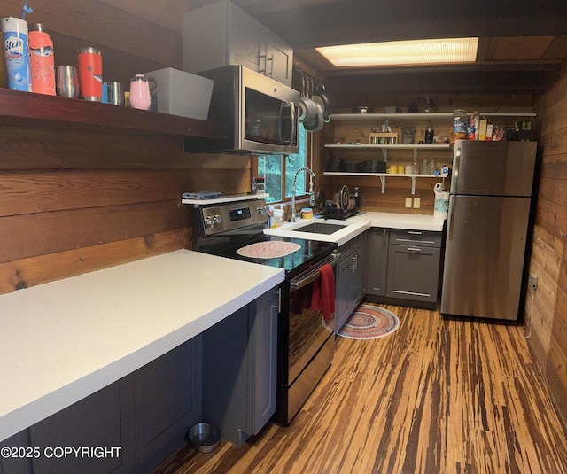 kitchen with open shelves, wooden walls, stainless steel appliances, and a sink