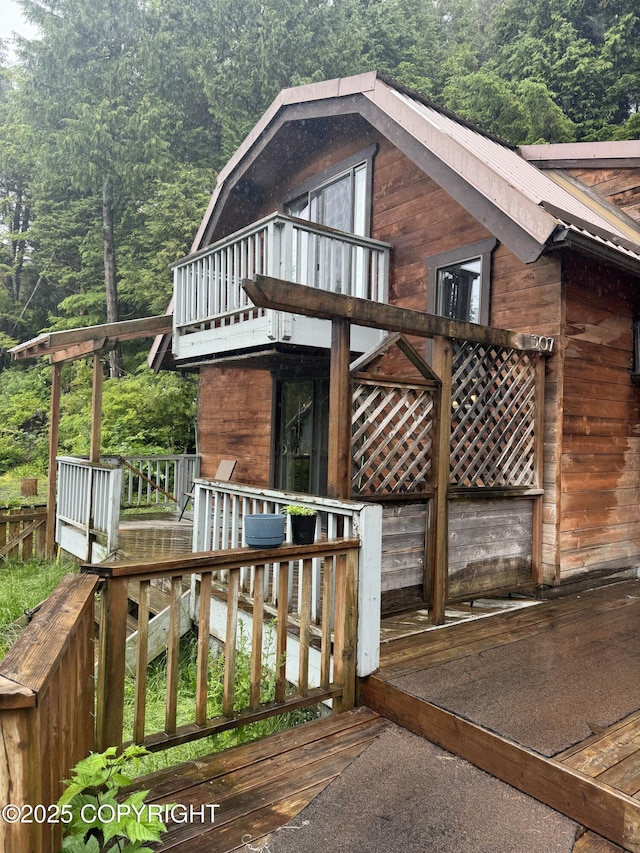 view of home's exterior with metal roof, a wooded view, and a balcony