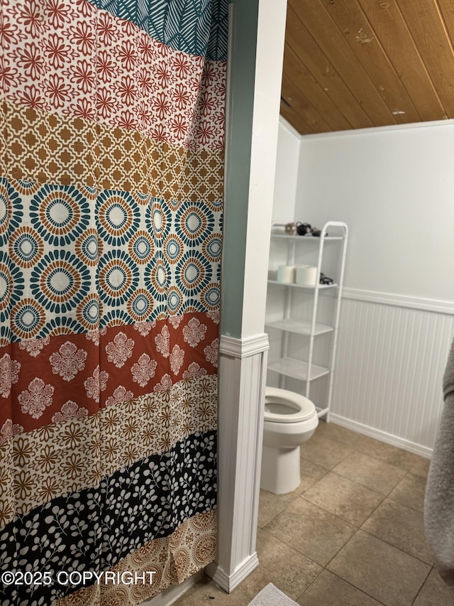 full bath with a wainscoted wall, toilet, wood ceiling, and a shower with curtain