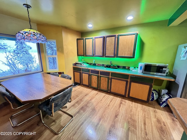 kitchen with light wood finished floors, recessed lighting, stainless steel microwave, and decorative light fixtures