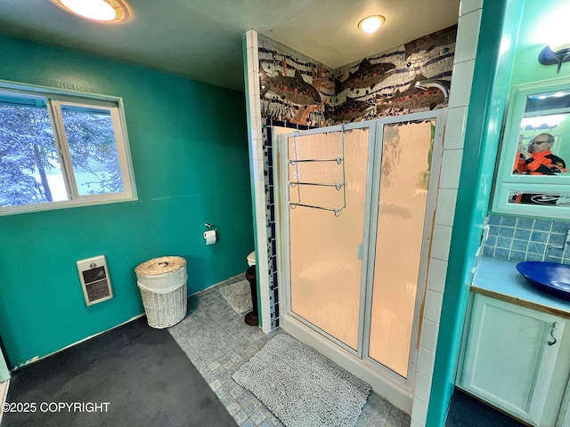 bathroom with a stall shower, a sink, and heating unit