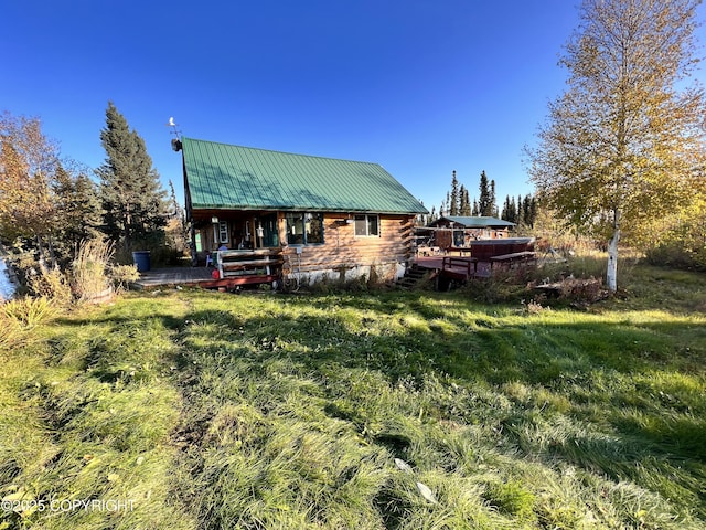 rear view of property featuring a deck, metal roof, log exterior, and a yard