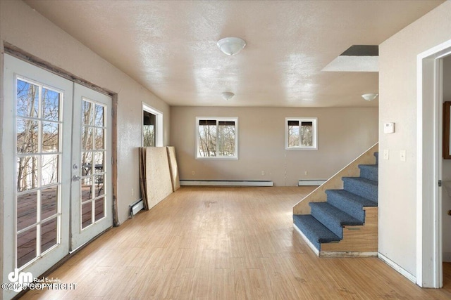 interior space featuring a baseboard radiator, a baseboard heating unit, wood finished floors, and stairs