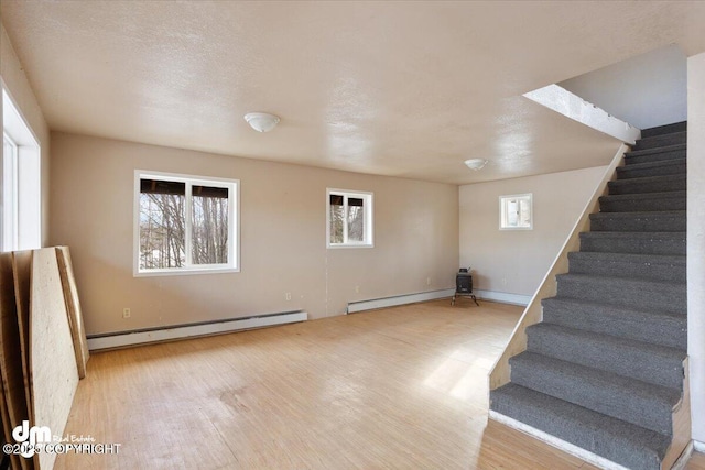 interior space with stairway, a baseboard heating unit, baseboards, and wood finished floors