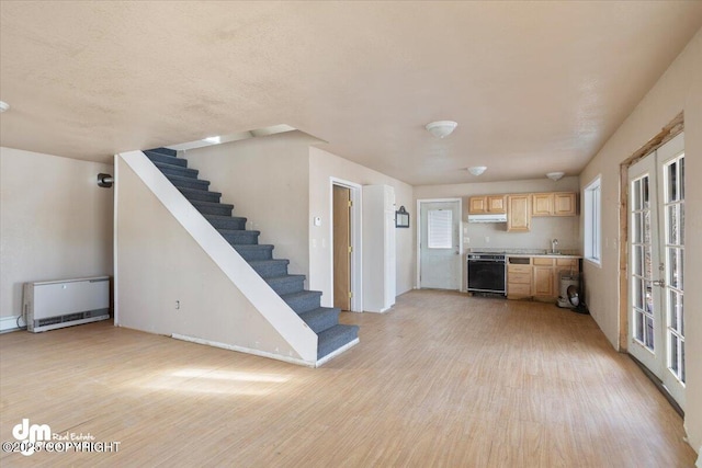 unfurnished living room featuring french doors, baseboards, light wood-type flooring, and stairway