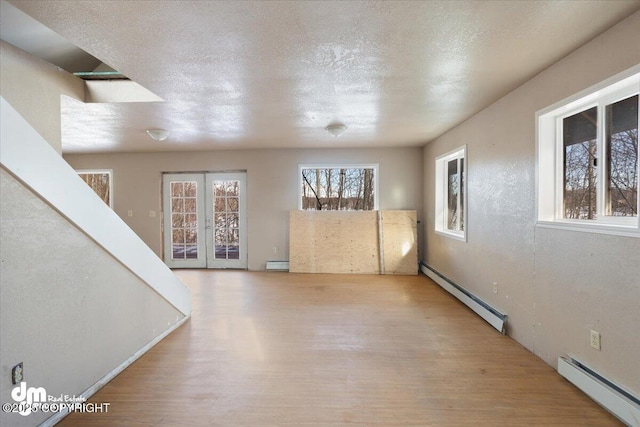 interior space featuring a textured ceiling, wood finished floors, a baseboard heating unit, a baseboard radiator, and french doors
