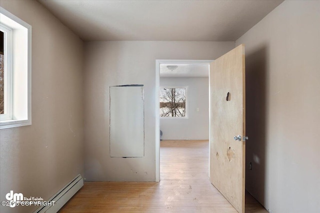 corridor with light wood finished floors and baseboard heating