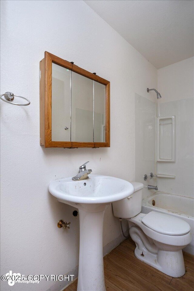 bathroom featuring toilet, wood finished floors, and shower / bathtub combination