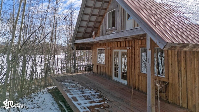 view of snowy exterior with french doors and a deck