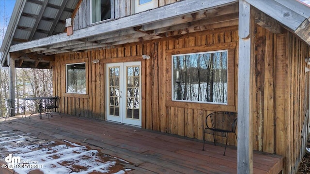 property entrance with board and batten siding, french doors, and a wooden deck