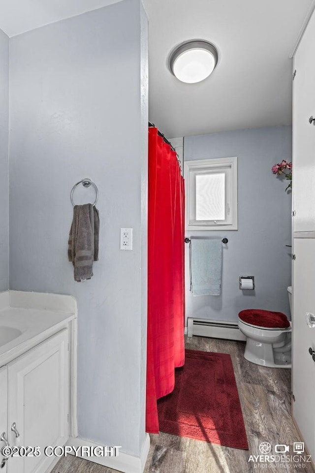 bathroom featuring a shower with shower curtain, toilet, vanity, and a baseboard radiator