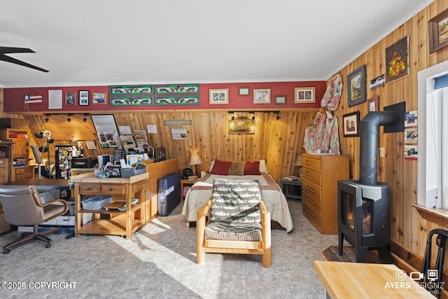 home office with a wood stove, wooden walls, and a ceiling fan