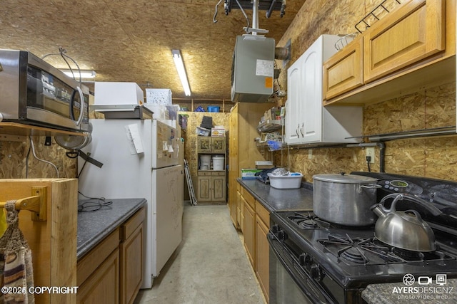 kitchen featuring concrete floors, dark countertops, black range with gas stovetop, and freestanding refrigerator